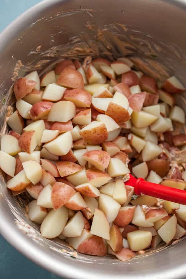 Adding cooked potatoes to the potato salad.