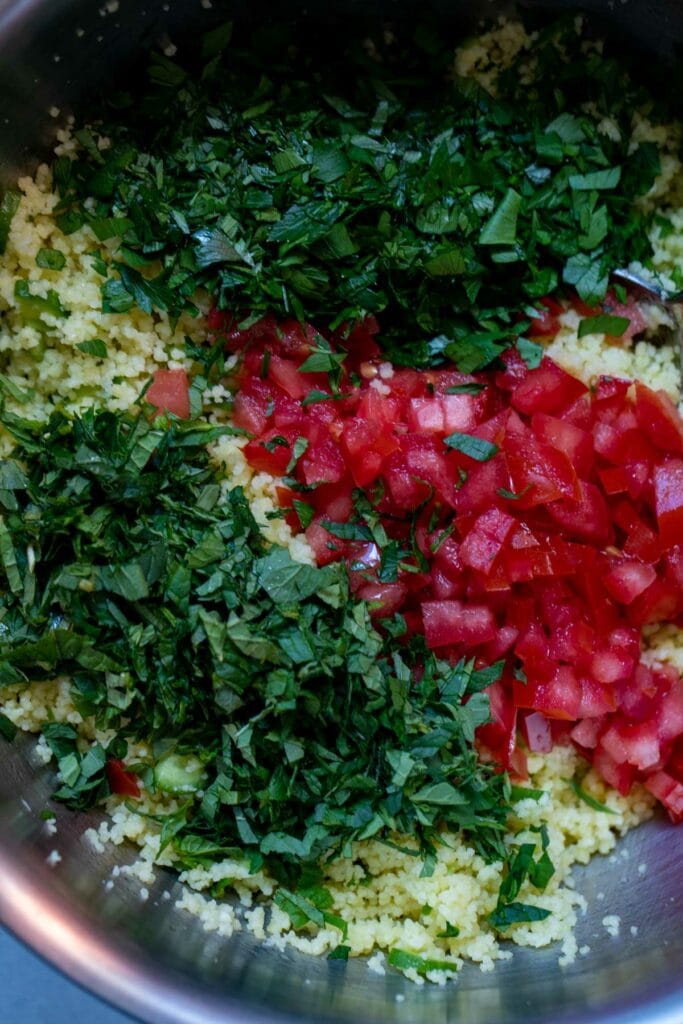 Mixing all the vegetables into the tabbouleh salad.