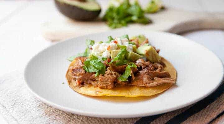 Traditional pork tinga simmered with peppers and spices and served on tostadas with classic toppings. Via Macheesmo.