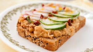Breakfast White Bean Toasts: Creamy and savory white beans mashed together with sun-dried tomatoes and shallots and served on toast with a crispy fried egg and thin, crunchy veggies. A great hearty breakfast and it's a quick 15 minute prep!