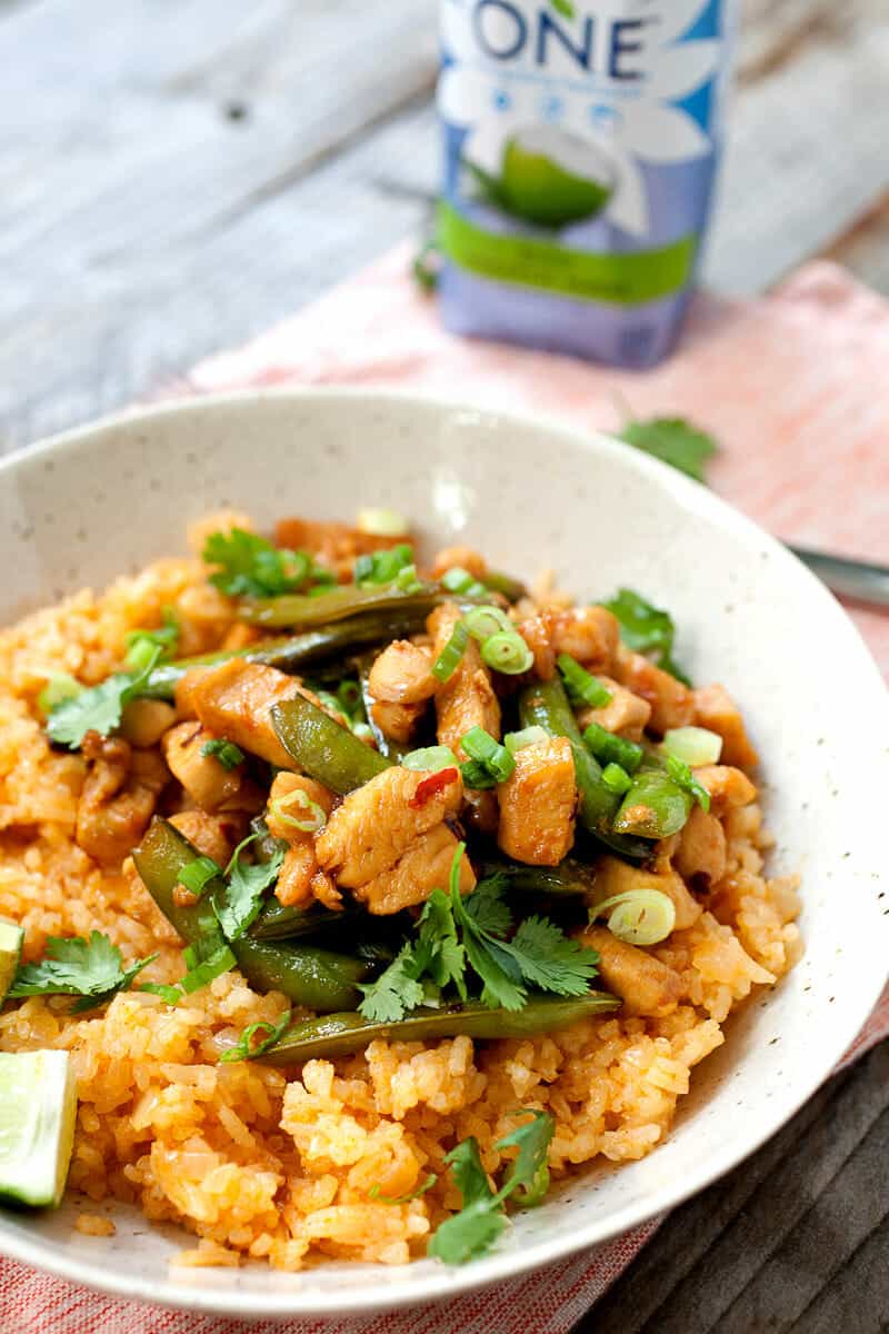 Coconut Rice Chicken Bowls: This coconut rice, made with coconut water instead of coconut milk, is light and flavorful with just a touch of spice. On top: chicken, snap peas, and an easy sauce. Takes about 30 minutes and better than take-out! Sponsored by @onecoconutwater | macheesmo.com