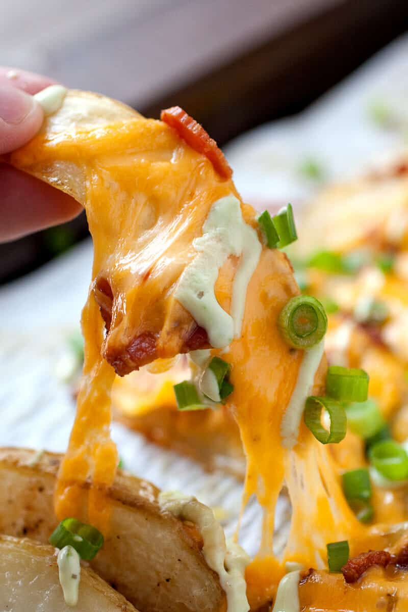 Loaded Potato Wedges - Appetizer? Side dish? Main meal? These completely loaded baked potato wedges can be anything you want. Cheddar, bacon, chives, and an avocado sour cream sauce. Potato perfection! | macheesmo.com