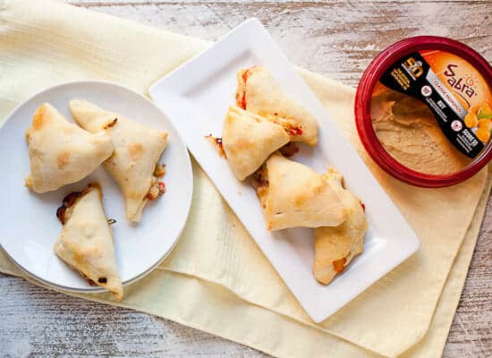 Hummus Pizza Pockets: A change-up on pizza! Perfect for a game-day appetizer. These bite-sized pizza pockets are stuffed with Mediterranean flavors like artichokes, olives, and tomatoes and have just enough hummus and cheese to act as a sauce. Fun to make and totally delicious! #sponsored | macheesmo.com