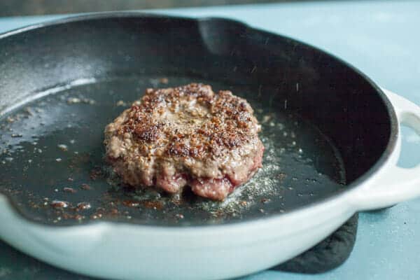 Cooking butter burger in cast iron skillet.