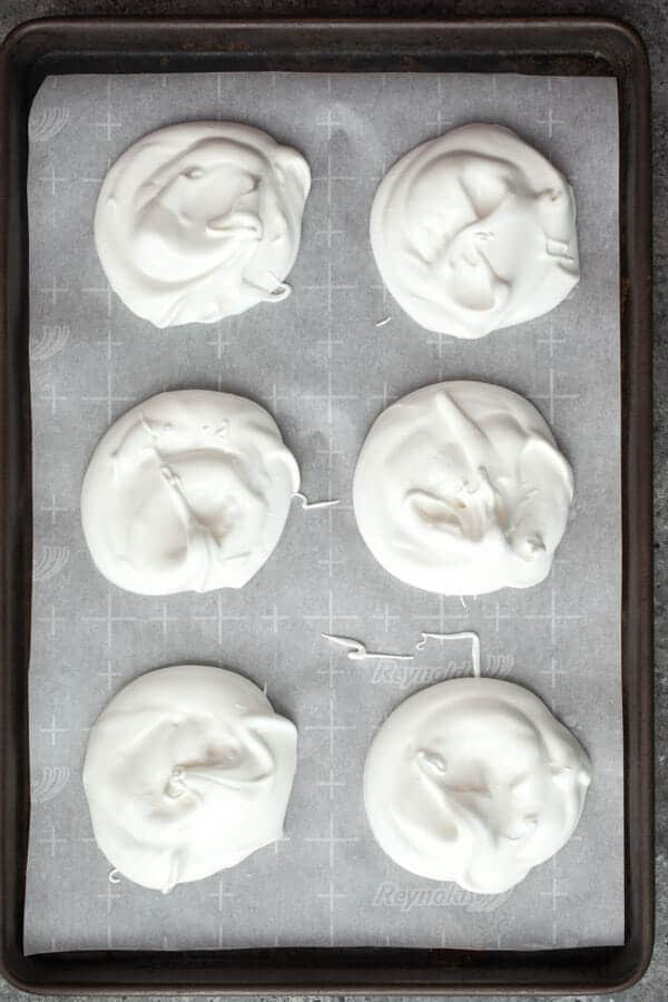 Mini pavlovas ready to bake in parchment paper.