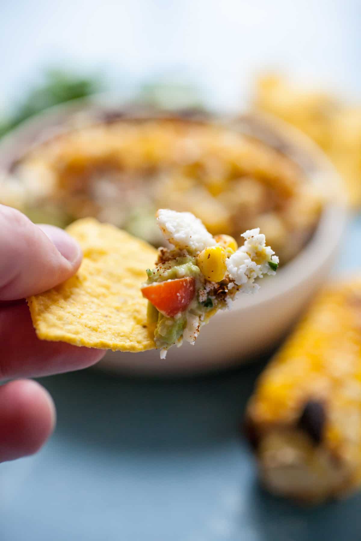 Street Corn Guacamole: Homemade guacamole mixed with a few simple, but perfect add-ins that mimic Mexican street corn (elote)! Roasted corn, cotija cheese, chili powder, cilantro, and a few other goodies. Perfect for a party! | macheesmo.com