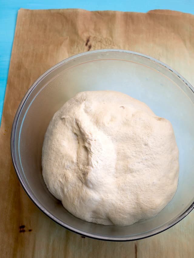 A ball of pizza dough in a glass bowl 
