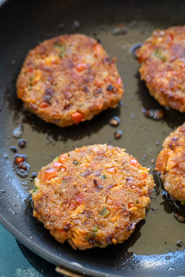 Cooking spicy salmon cakes in a skillet.