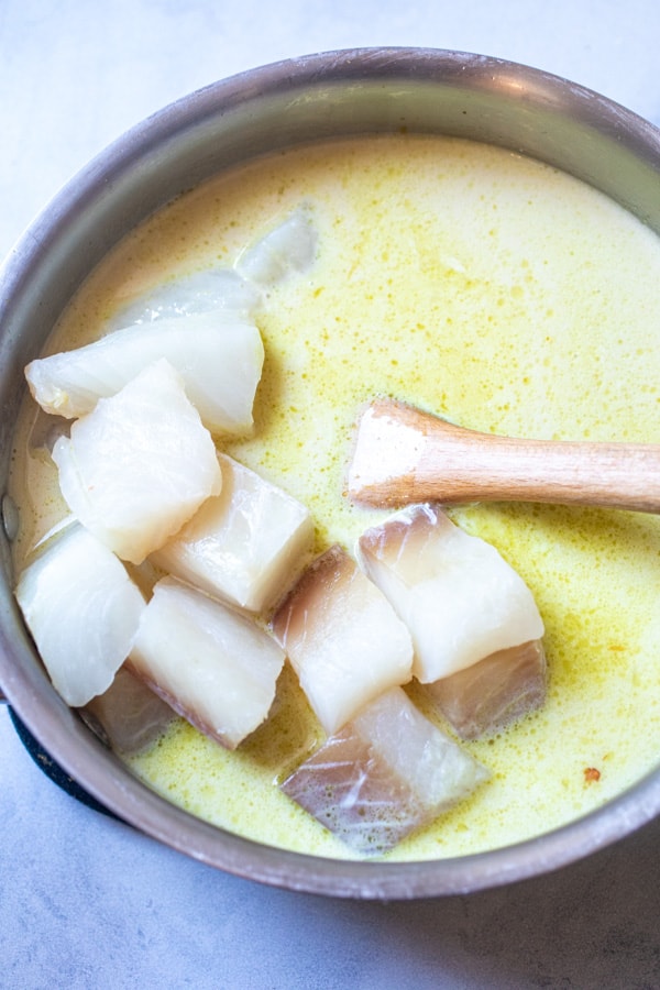 Adding cubed cod to curry.