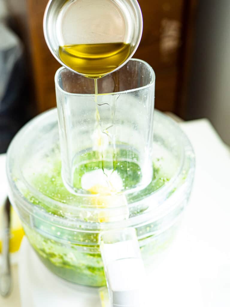 Olive oil drizzling into the food processor to make pesto