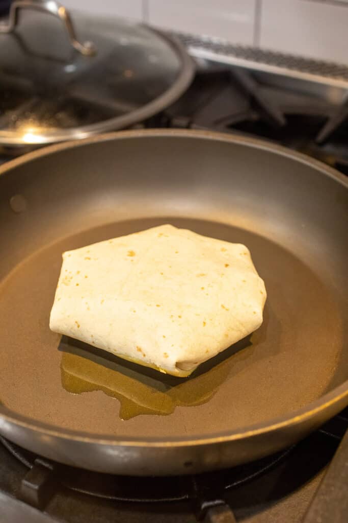 Sealing crunch wrap in a skillet.
