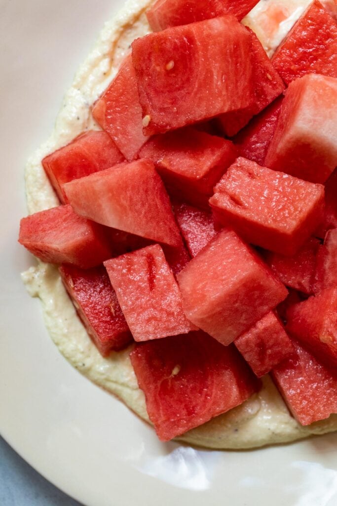 Adding watermelon cubes to whipped feta.