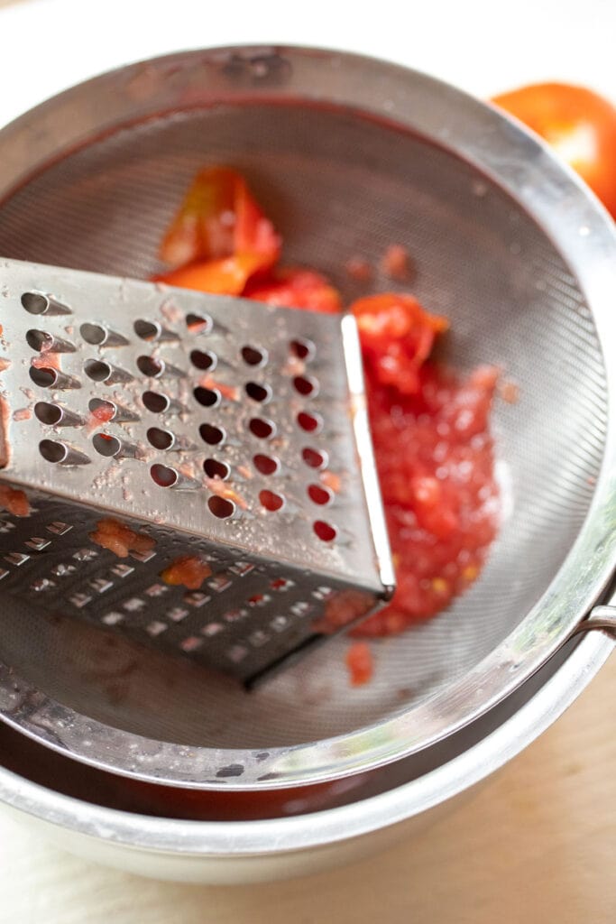 Grating tomatoes for toasts.
