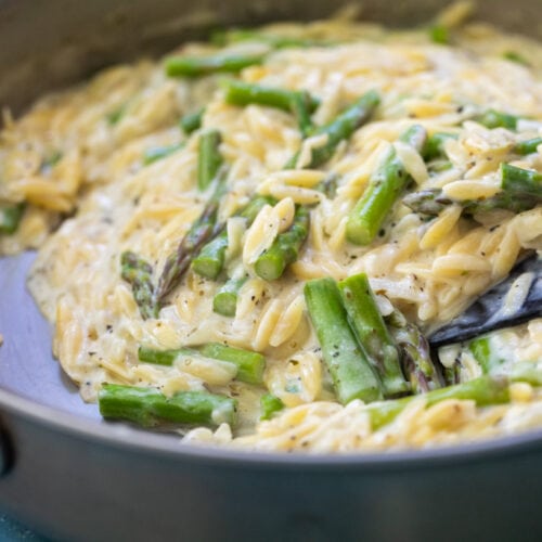 Creamy orzo with asparagus in a skillet.
